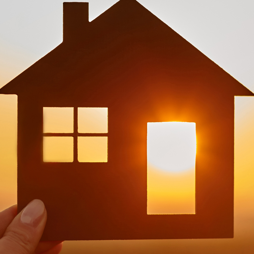 Person holding cutout of home with Sun shining through