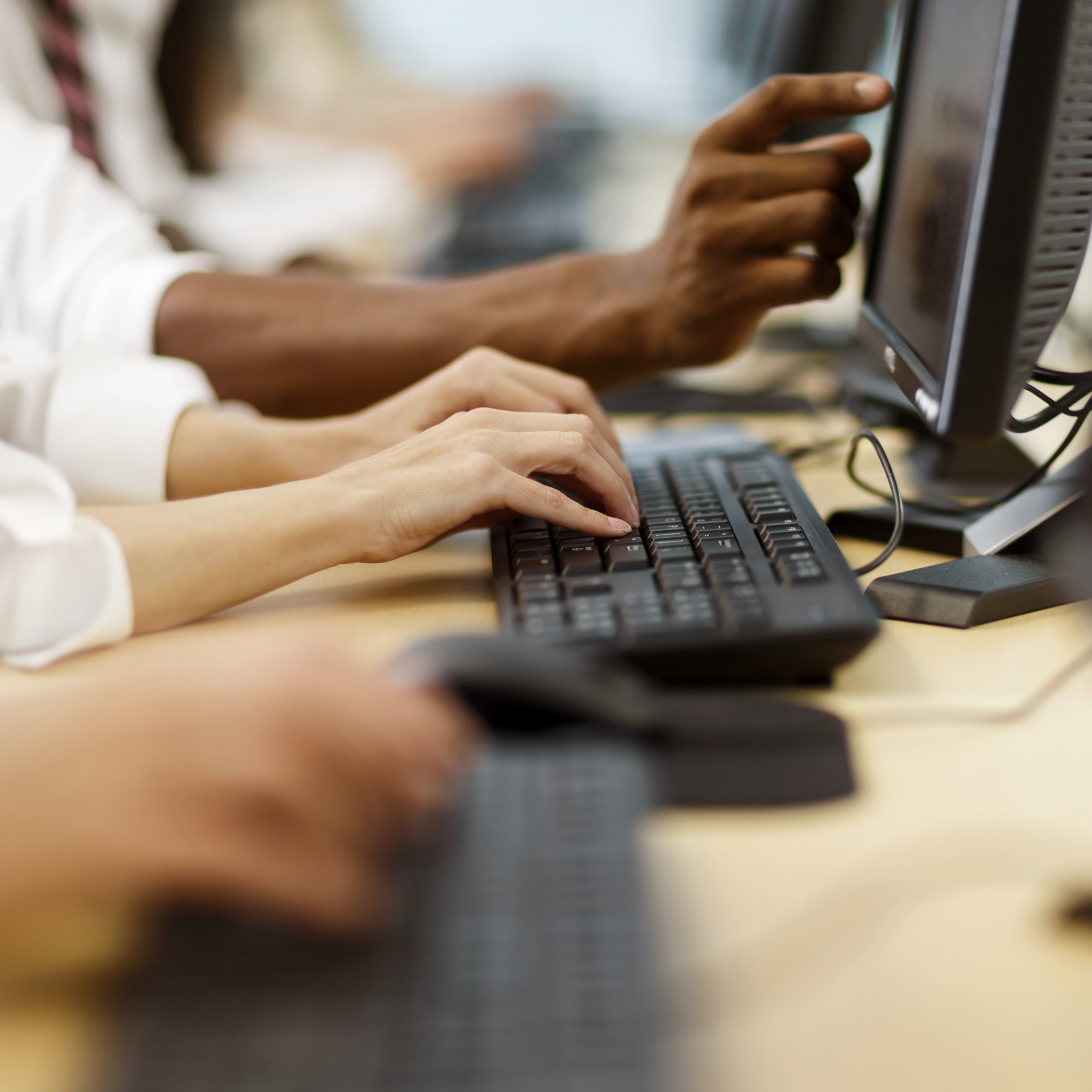 People in front of computer screens working together